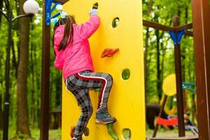 niña feliz en un parque de cuerdas en el fondo de madera foto