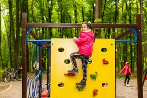 happy little girl in a rope park on the wood background photo