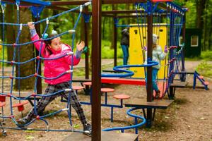 happy little girl in a rope park on the wood background photo