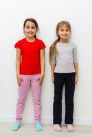 Two cute little girls in full growth, in the studio on a white background. The concept of a happy childhood, Beauty and fashion. Isolated. photo