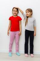 Two girls stretch up with hand on scale photo