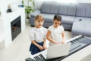 Home piano lesson. two girls practice sheet music on one musical instrument. Family concept. The idea of activities for children during quarantine. photo