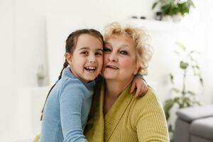 retrato de contento antiguo abuela y niño niña mirando a cámara, sonriente abuela con nieta haciendo vídeo llamar, niño y abuelita vloggers grabación vídeo Blog o vlog juntos foto