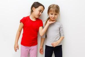 Cute little caucasian girls are keeping hands up, looking at camera and smiling, isolated on a white background photo