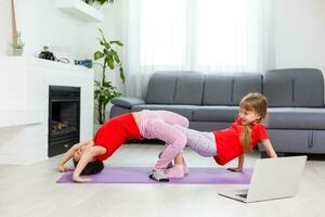 Beautiful athletic young girls practicing yoga together at home photo