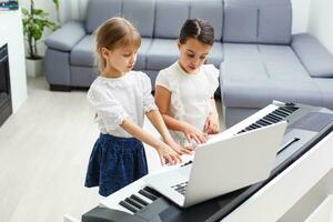 Home lesson on music for the girl on the piano. The idea of activities for the child at home during quarantine. Music concept photo