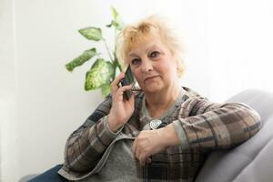 Happy senior woman talking on smartphone at home. photo