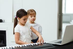 Home lesson on music for the girl on the piano. The idea of activities for the child at home during quarantine. Music concept photo