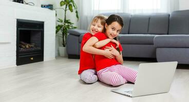 Two little girls are playing with laptop in playroom at home photo