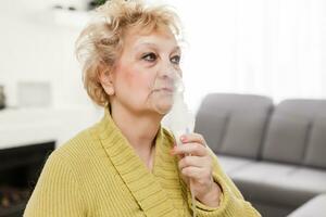 de cerca retrato de un mayor mujer en un médico mascarilla. el utilizar de el nebulizador. foto