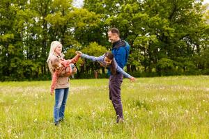 young familiy are walking through a green field photo