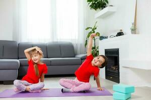 Beautiful athletic young girls practicing yoga together at home photo