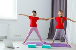 Beautiful athletic young girls practicing yoga together at home photo