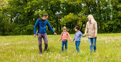 young familiy are walking through a green field photo