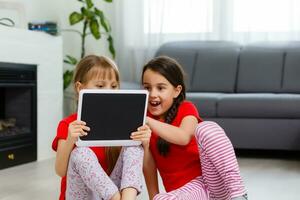 Little girls playing on a tablet computing device sitting on the floor photo