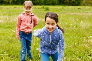 Two sisters hug one another outdoors, happy family photo