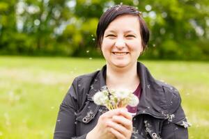 Girl blowing on white dandelion in the forest photo