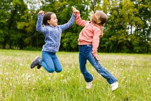 Two sisters hug one another outdoors, happy family photo