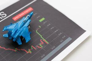 Tablet with stock data on table and a toy airplane photo