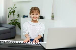 Home lesson on music for the girl on the piano. The idea of activities for the child at home during quarantine. Music concept photo