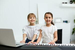 Home piano lesson. two girls practice sheet music on one musical instrument. Family concept. The idea of activities for children during quarantine. photo