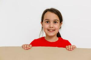 A cheerful child sits inside a mail box. The head of a little girl peeks out of a corton box. The baby arrived in a new house in a postal parcel. Portrait of a child with blue eyes. photo