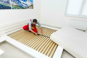 Man's hands working with a hex key. Assembling furniture. Wooden plank of a bed. Close up. photo