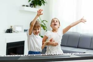 Home piano lesson. two girls practice sheet music on one musical instrument. Family concept. The idea of activities for children during quarantine. photo