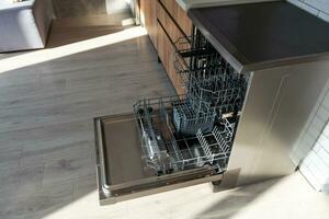 Open dishwasher with clean dishes in the white kitchen. photo