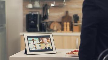 negocio mujer utilizando inteligente dispositivo mientras comiendo desayuno en cocina. joven persona de libre dedicación a hogar hablando en un vídeo llamada con su colegas desde el oficina, utilizando moderno Internet tecnología foto