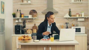 mujer de negocios haciendo en línea pago utilizando crédito tarjeta en un ordenador portátil durante desayuno. compras en línea para bienes y ropa, utilizando moderno tecnología en cada día vida, haciendo pagos vía Internet foto