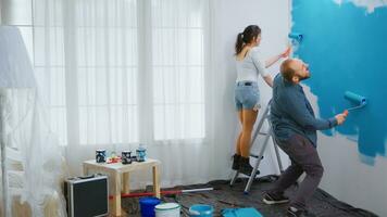 Cheerful couple painting and dancing while redecorating living room. Happy family. Apartment redecoration and home construction while renovating and improving. Repair and decorating. photo