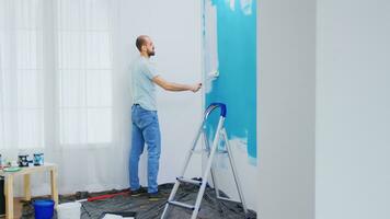 Painting apartment wall with white paint using roller brush. Handyman renovating. Apartment redecoration and home construction while renovating and improving. Repair and decorating. photo