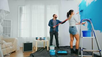 Husband and wife changing wall color using roller brush during home renovation. Home decoration and renovation in cozy apartment flat, repair and makeover photo