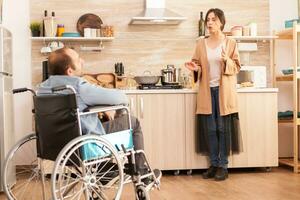 Disabled man in wheelchair having a conflict with wife in kitchen. Disabled paralyzed handicapped man with walking disability integrating after an accident. photo