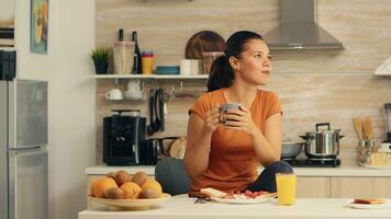 Woman drinking hot coffee at breakfast in kitchen and delicious food on table top. Lady ejoying a cup of coffee in the morning. Happy housewife relaxing and spoiling herself with a healthy meal alone photo