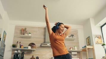 Cheerful woman singing in the kitchen in the morning. Energetic, positive, happy, funny and cute housewife dancing alone in the house. Entertainment and leiuse alone at home photo