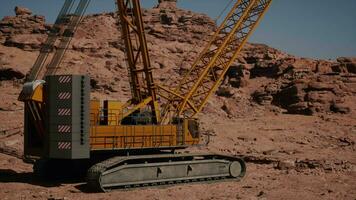 A large yellow crane sitting on top of a rocky hillside video