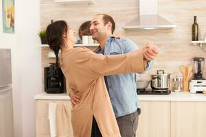 alegre Pareja sonriente y bailando en cocina. romántico marido y esposa. esposa y marido amar, romance, oferta momento, divertido y felicidad a hogar, unión música alegre y sonrisa foto