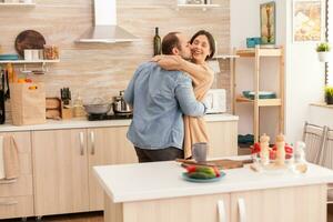 Man kissing wife in kitchen during romantic dance in kitchen. Wife and husband love, romance, tender moment, fun and happiness at home, togetherness music cheerful and smile photo