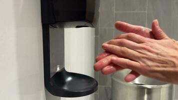 Close-up of a woman's hands being treated with antiseptic from a wall-mounted dispenser. Touch dispenser for antibacterial agents in a public place. video