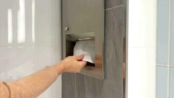 Close-up of a woman's hands pulling paper napkins from a wall-mounted box. White paper towel dispenser on the wall. Healthcare and prevention concept. video