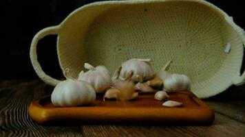 Garlic cloves falling on a wooden plate surrounded by garlic video