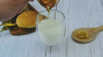 Frühstück einstellen männlich Hand Gießen Honig in ein Glas von Milch mit Brot video