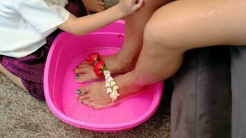 asiatico ragazzo lavaggio il suo La madre di piedi per mostrare il suo amore su La madre di giorno. video