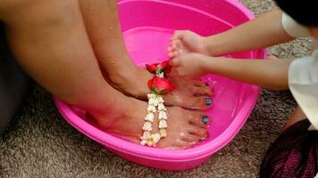 ásia Garoto lavando dele mãe pés para mostrar dele amor em mãe dia. video