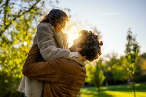 Portrait of happy loving couple in park in sunset. Man is holding his woman in hands. photo