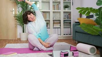 calm of her living room, a woman stretches gracefully, glow of screen guiding through yoga sequence video