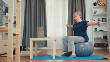 Healthy senior woman exercising with dumbbells in living room. Old person online internet training at home sport healthy lifestyle, elderly fitness exercise workout in apartment, activity and healthcare photo