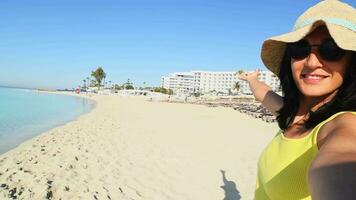 Happy young tourist taking selfie pose at beach on vacation show hotel stay - Millennial girl having fun smiling at camera - People and holidays concept. Solo traveler explore video